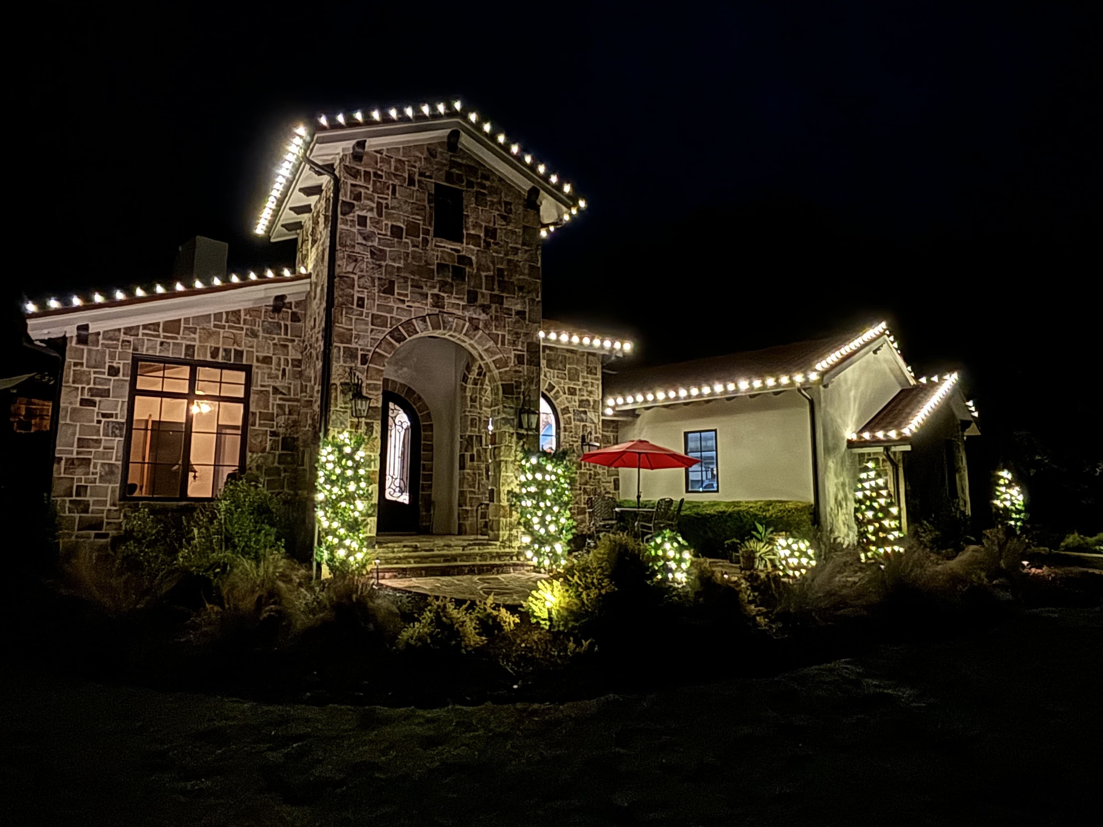 Elegant stone house beautifully illuminated with festive lights at night.